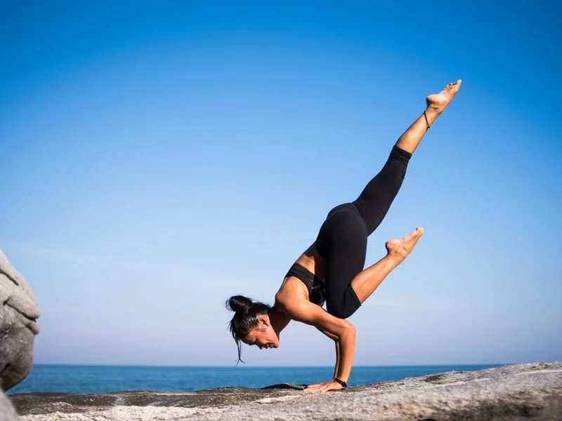 Persona practicando yoga junto al mar